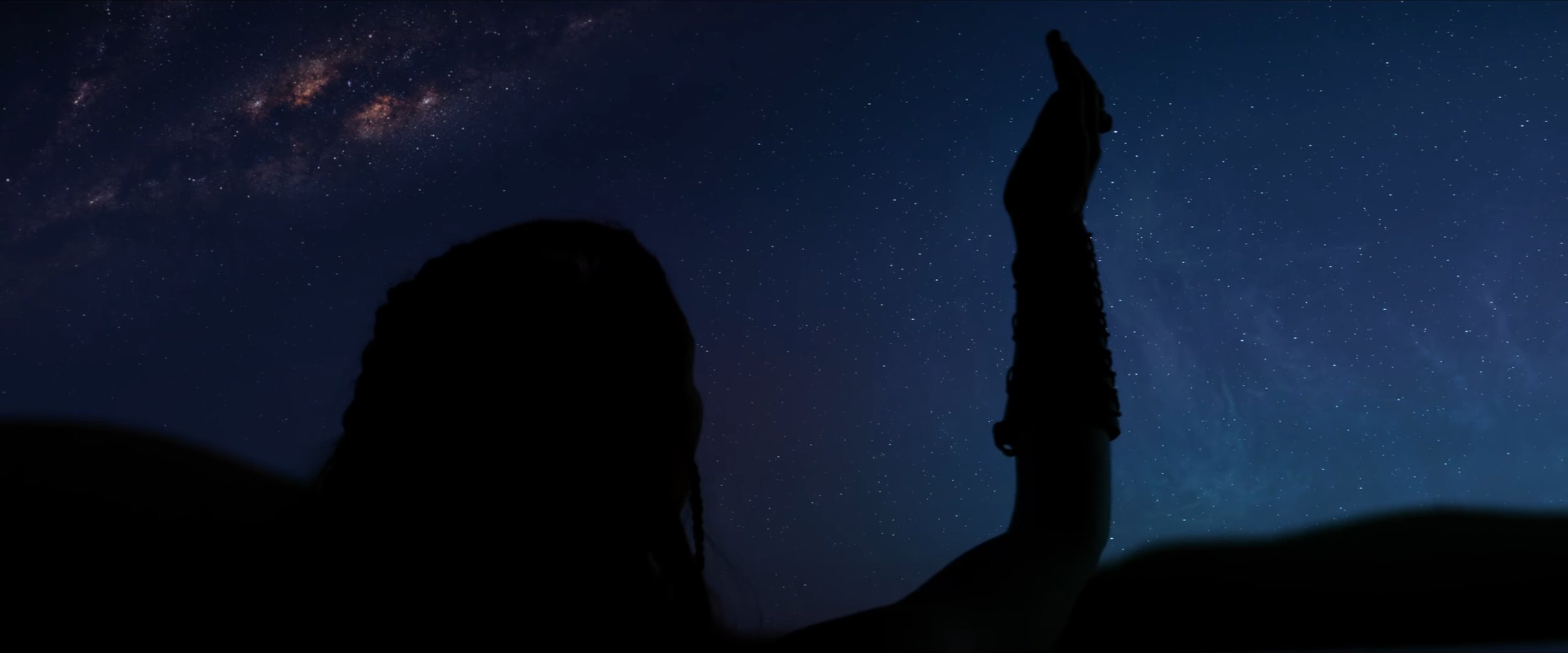 Production still — silhouette under the Milky Way