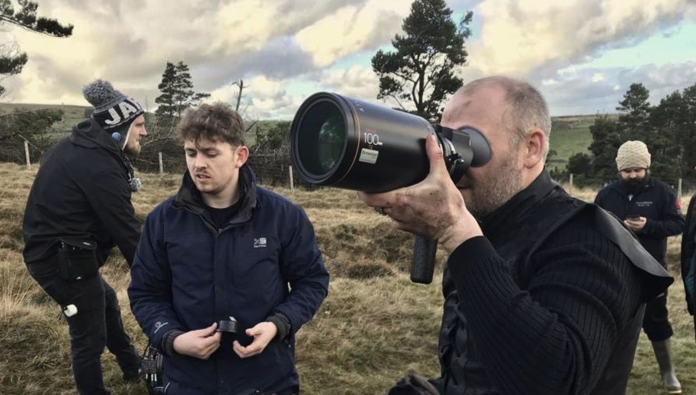 Crew with a long lens and sound kit shooting on a hillside